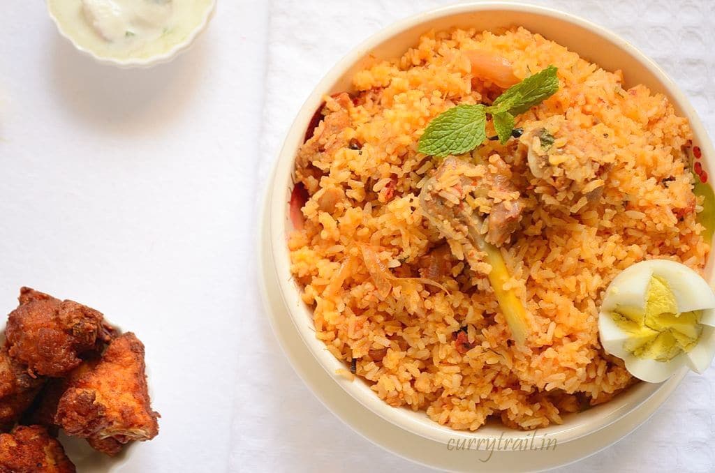 Ambur chicken biryani in a white bowl and fried chicken on the side