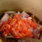 chopped onions and tomatoes is cooked in cooker for ambur chicken biryani