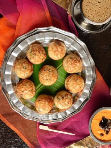 Oats paniyaram arranged in white metal plate with spicy chutney on the side and filter coffee