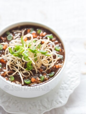 hot sour and spicy vegetable manchow soup topped with crunchy fried noodles served in white bowl