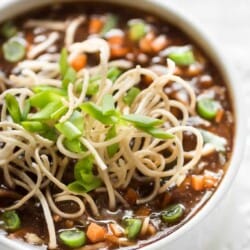 hot sour and spicy vegetable manchow soup topped with crunchy fried noodles served in white bowl