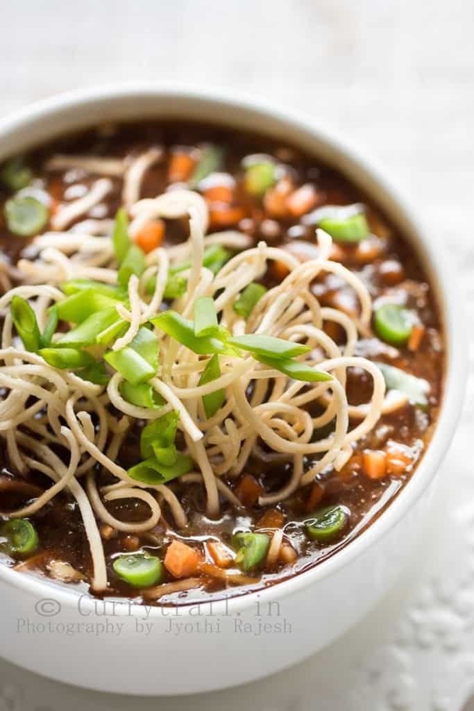 hot sour and spicy vegetable manchow soup topped with crunchy fried noodles served in white bowl