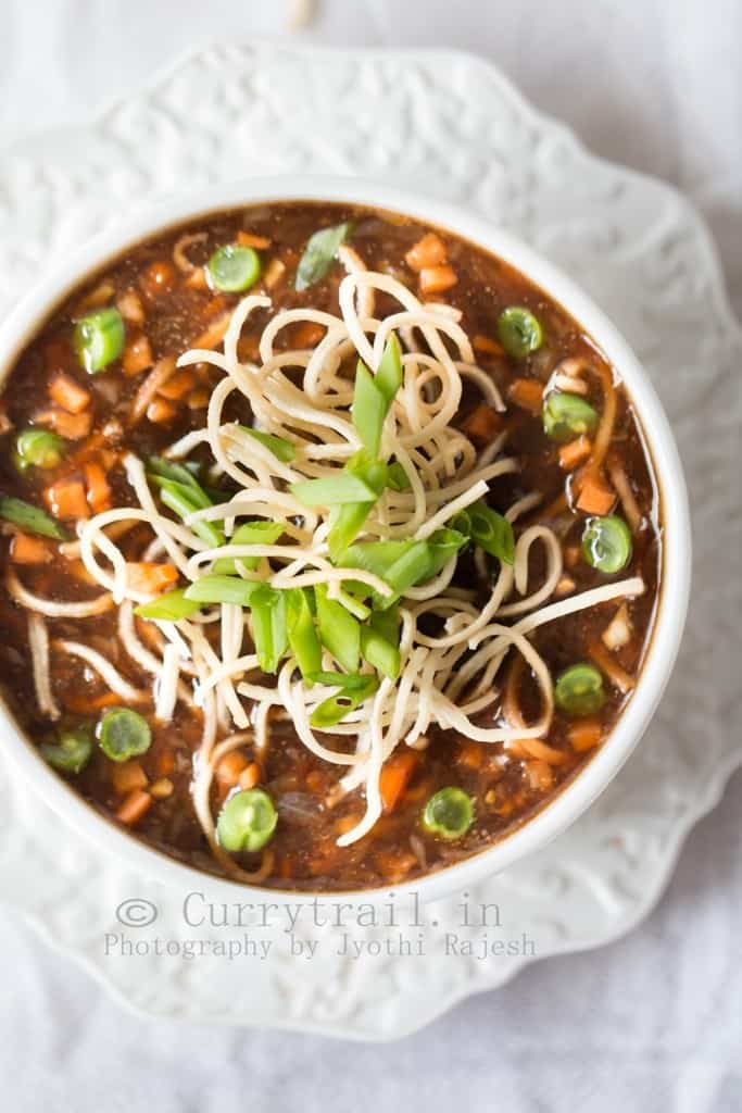 hot sour and spicy vegetable manchow soup topped with crunchy fried noodles served in white bowl