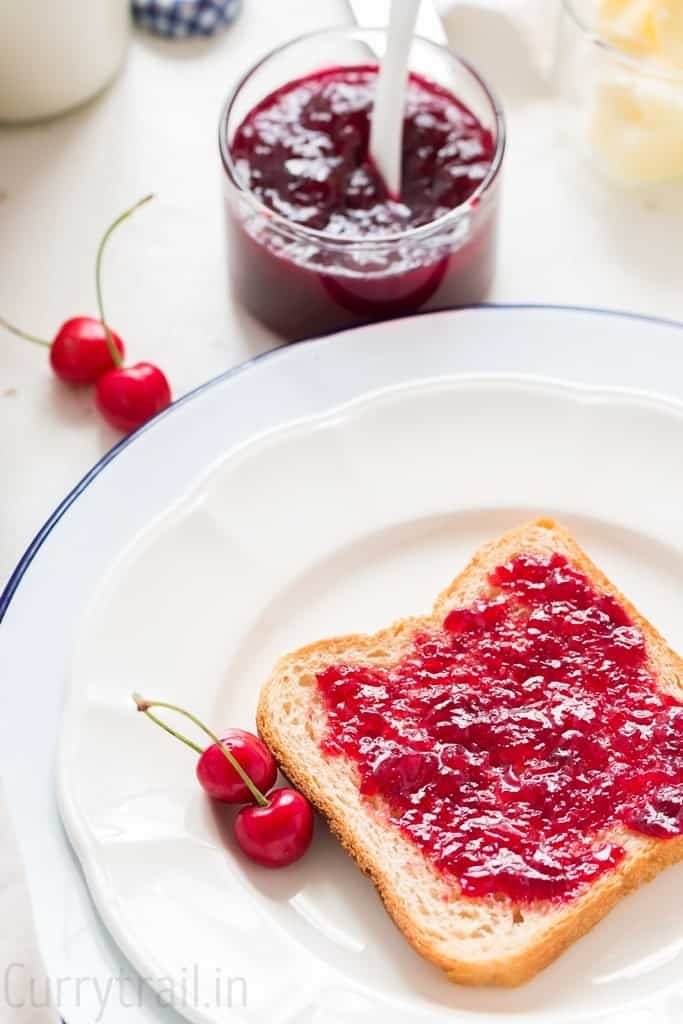 white plate with a bread slice smeared with homemade cherry jam