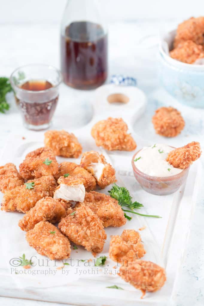 homemade chicken nuggets server on white tray with creamy spicy sauce on the side