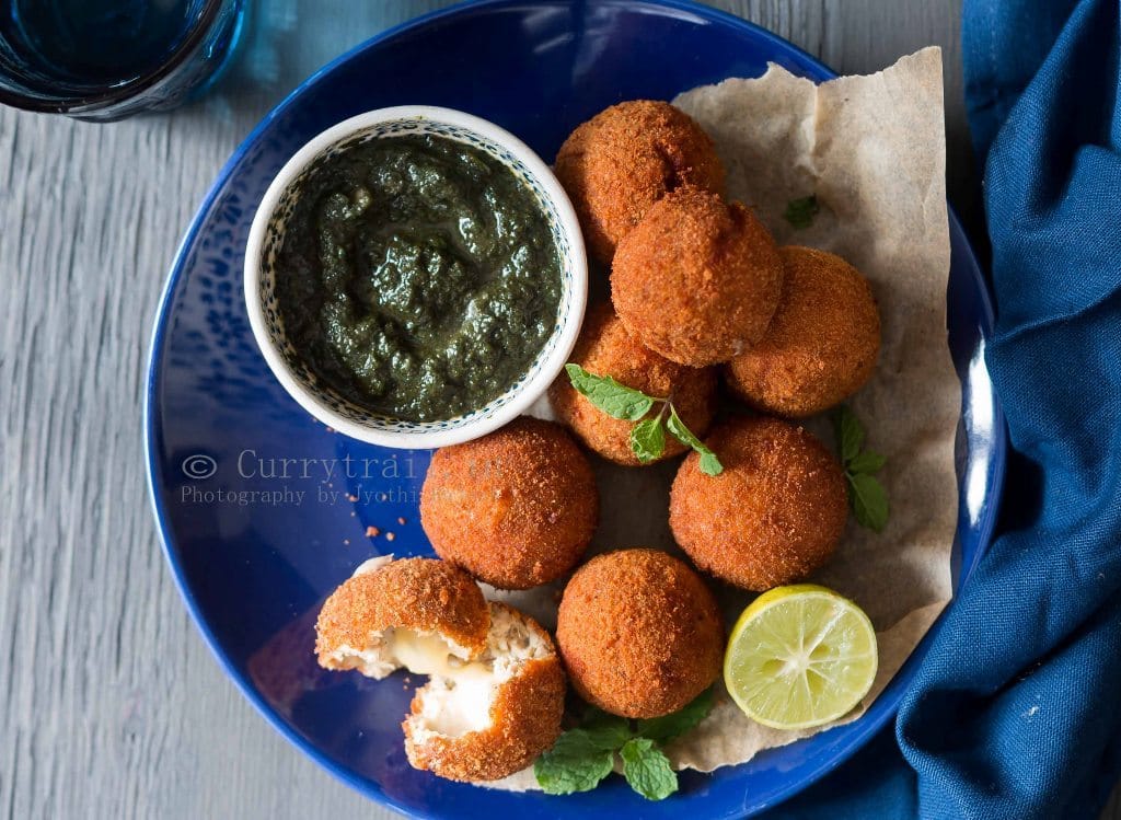 a blue plate with cheesy garlic chicken balls with a small bowl of mint sauce on side