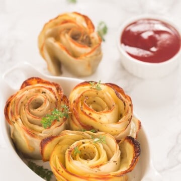 baked potato roses served in white oval ceramic dish with sauce on side