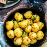 Jeera aloo in black cast iron pan with rotis on a plate