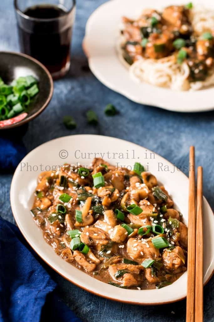 cantonese chicken with mushrooms served in white oval ceramic plate with chopsticks