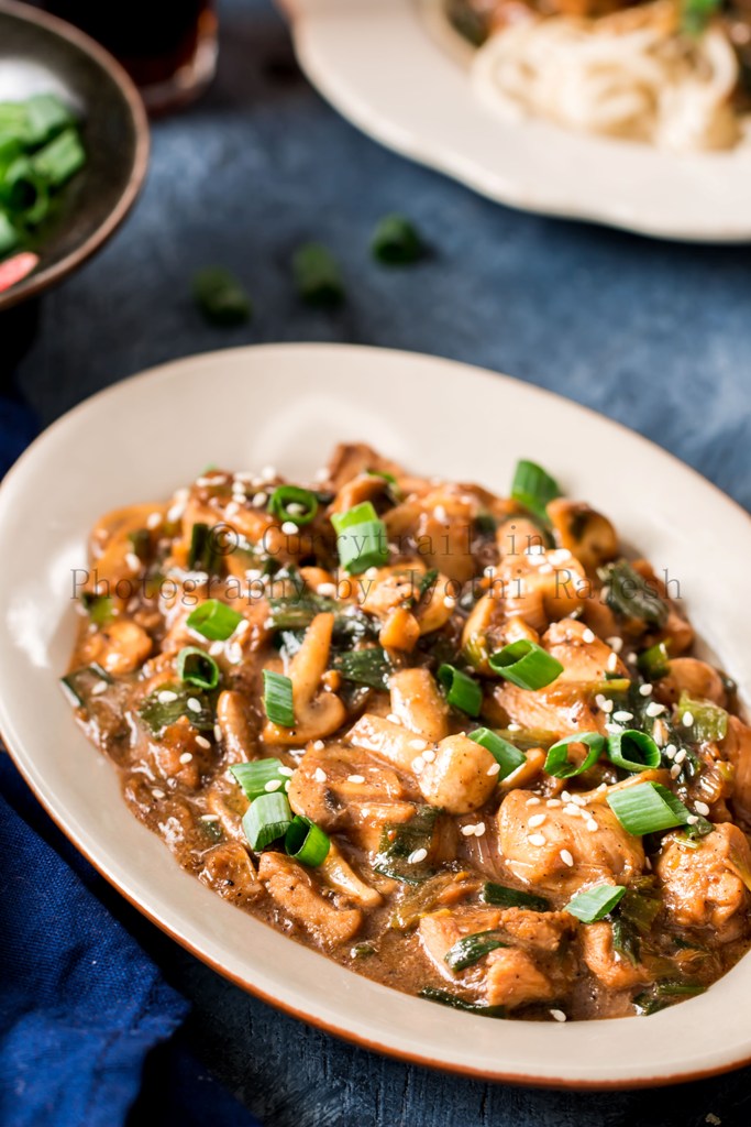 cantonese chicken with mushrooms served in white oval ceramic plate with chopsticks