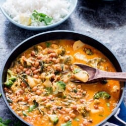 A pan with chickpea potato curry in broccoli spinach with spatula