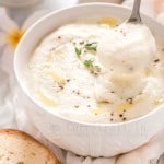spooning out creamy cauliflower soup from white bowl