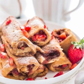 Close view of Nutella Strawberry French toast Roll Ups with cinnamon sugar sprinkled on top placed on white plate