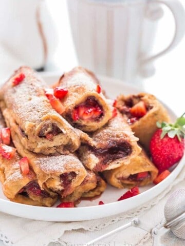 Close view of Nutella Strawberry French toast Roll Ups with cinnamon sugar sprinkled on top placed on white plate