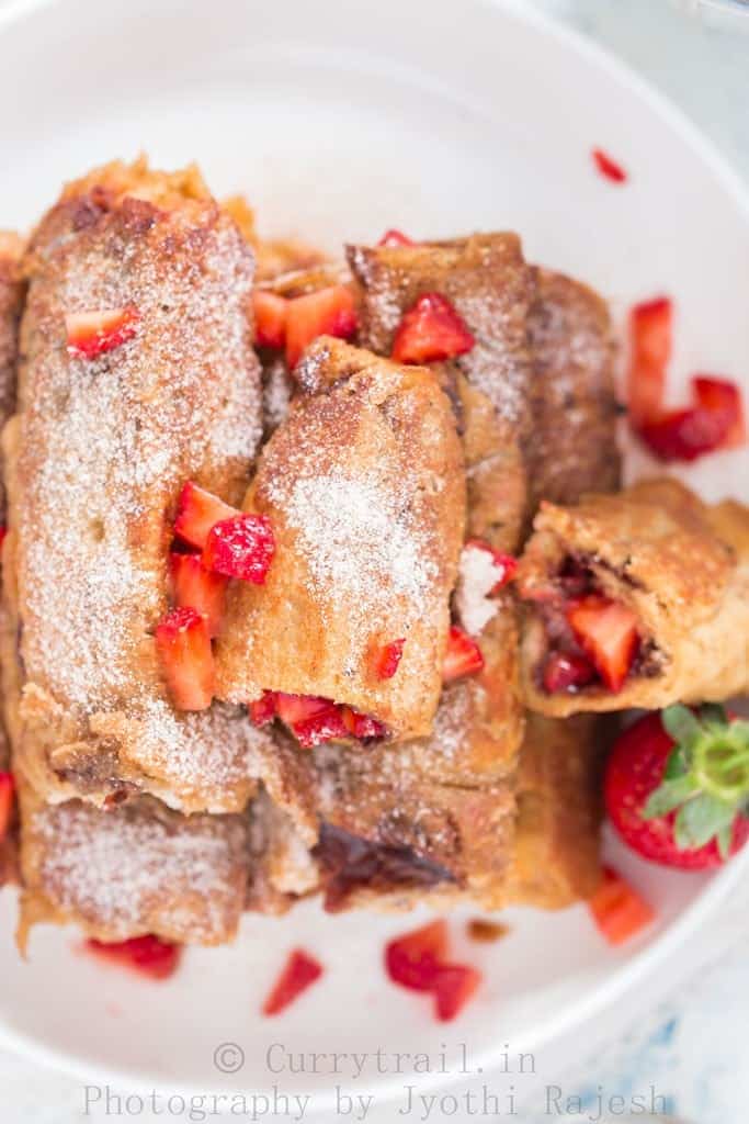 on a white plate Nutella Strawberry French toast Roll Ups stacked up