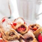 A plate full of Nutella Strawberry French toast Roll Ups with morning coffee on the back