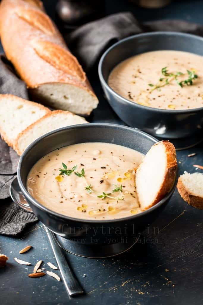 spiced roasted cauliflower soup served in 2 ceramic bowls with French baguette bread to dip in 