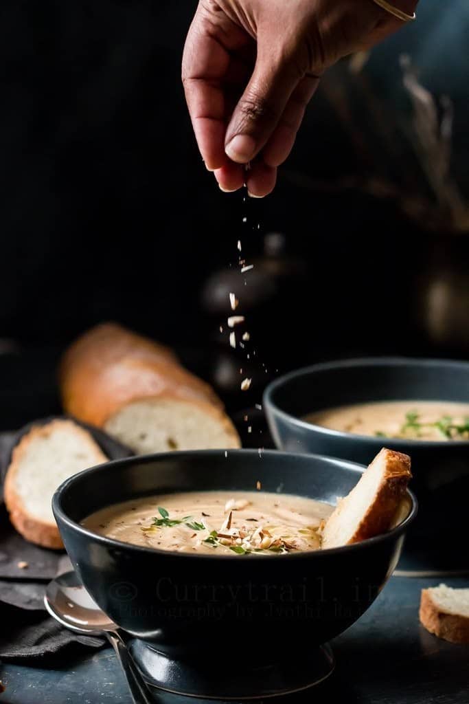 spiced roasted cauliflower soup served in ceramic bowls with almonds sprinkled from top