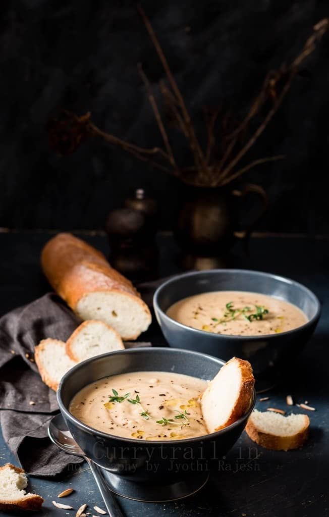 spiced roasted cauliflower soup served in 2 ceramic bowls with French baguette bread to dip in 