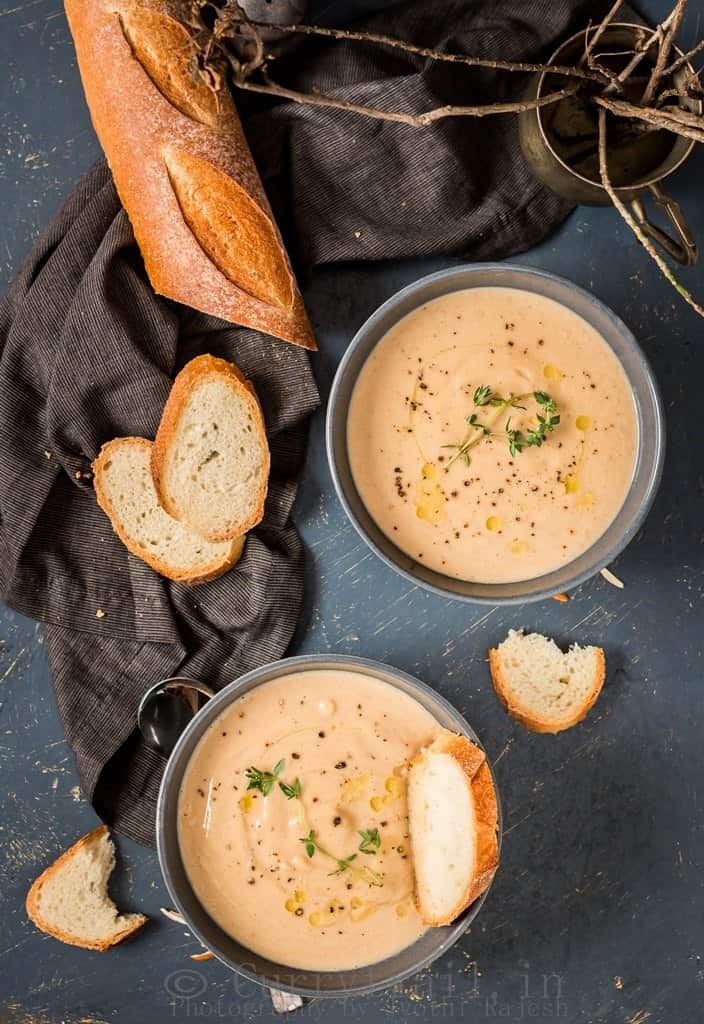 spiced roasted cauliflower soup served in 2 ceramic bowls with French baguette bread to dip in 
