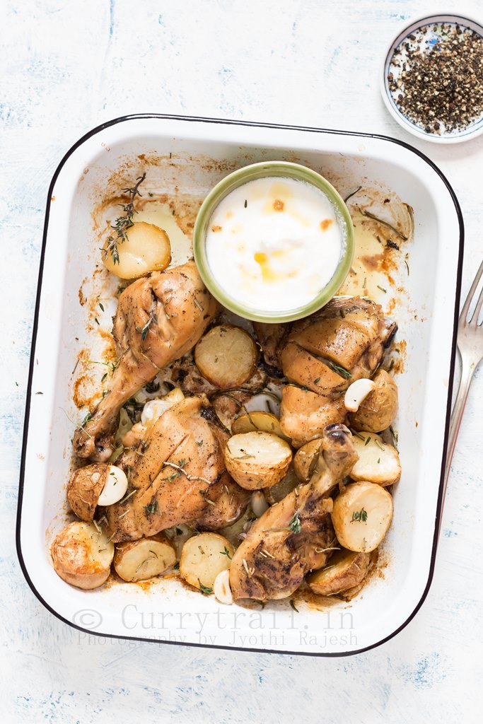 Lebanese style baked chicken and potatoes served in white enamel plate with garlicky sauce on the side
