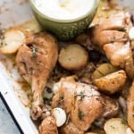 Lebanese style baked chicken and potatoes served in white enamel plate with garlicky sauce on the side