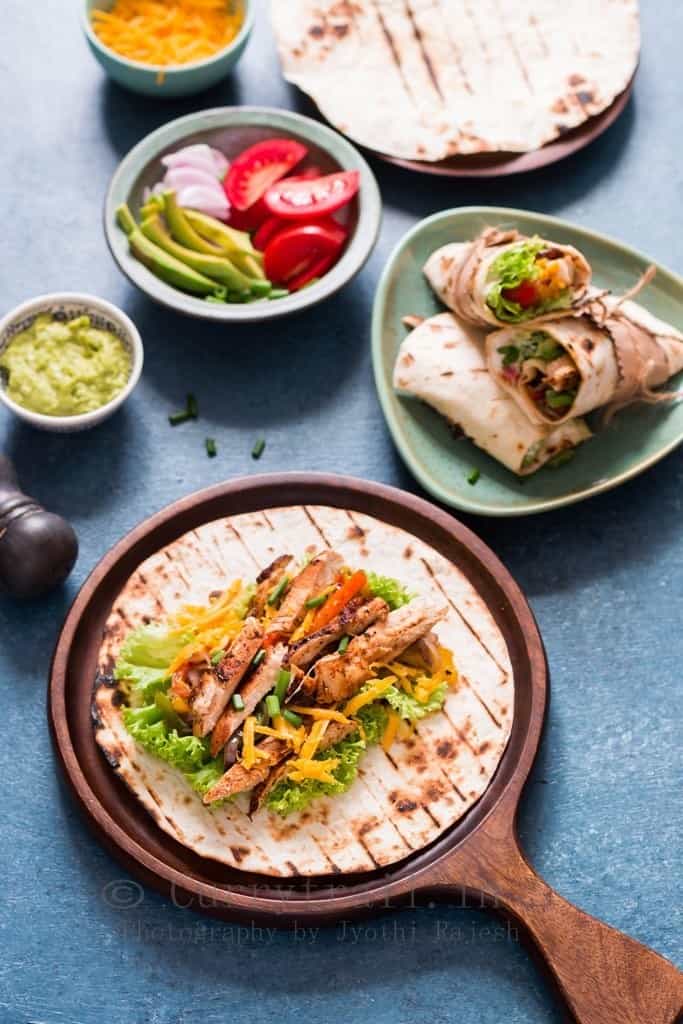 Flour tortillas with chicken fajitas with a plate and bowls around