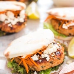 Moroccan Chicken Burgers Spread on a Boards with Bowl of Carrots close up view
