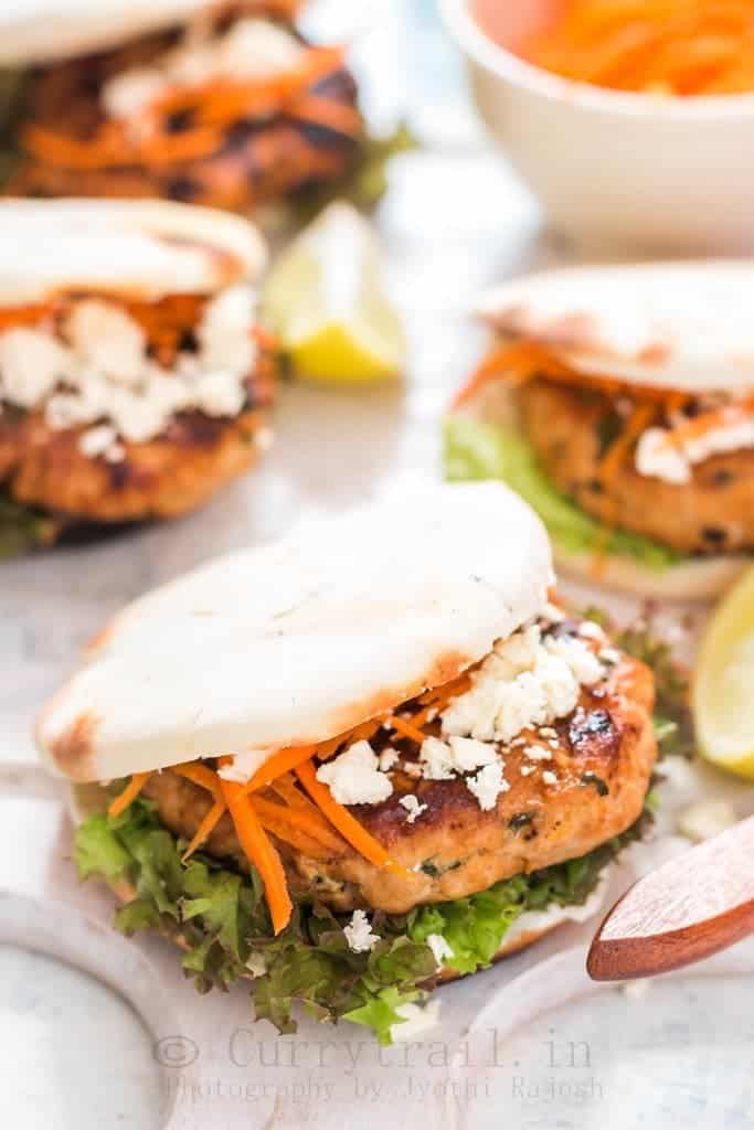 Moroccan Chicken Burgers Spread on a Boards with Bowl of Carrots close up view
