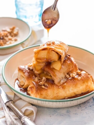 apple pie enchilafa with nuts on top drizzled with brown butter sauce