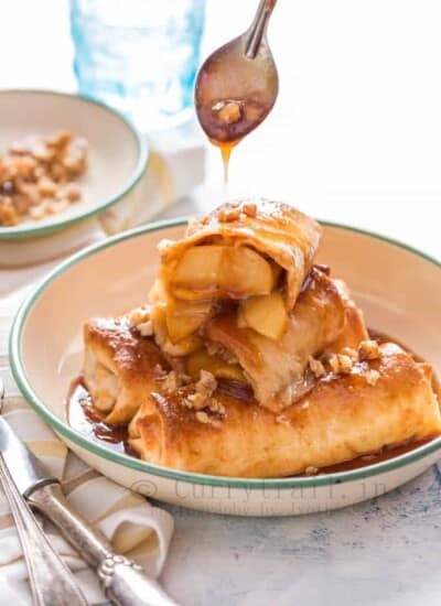apple pie enchilafa with nuts on top drizzled with brown butter sauce