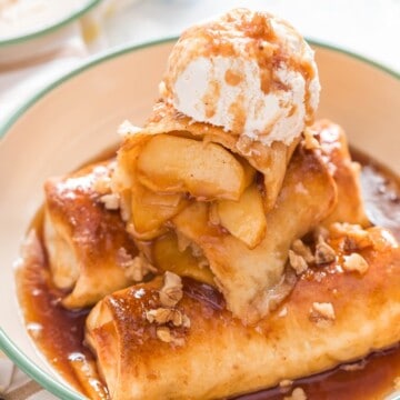 apple pie enchilafa with nuts on top drizzled with brown butter sauce and served with ice cream