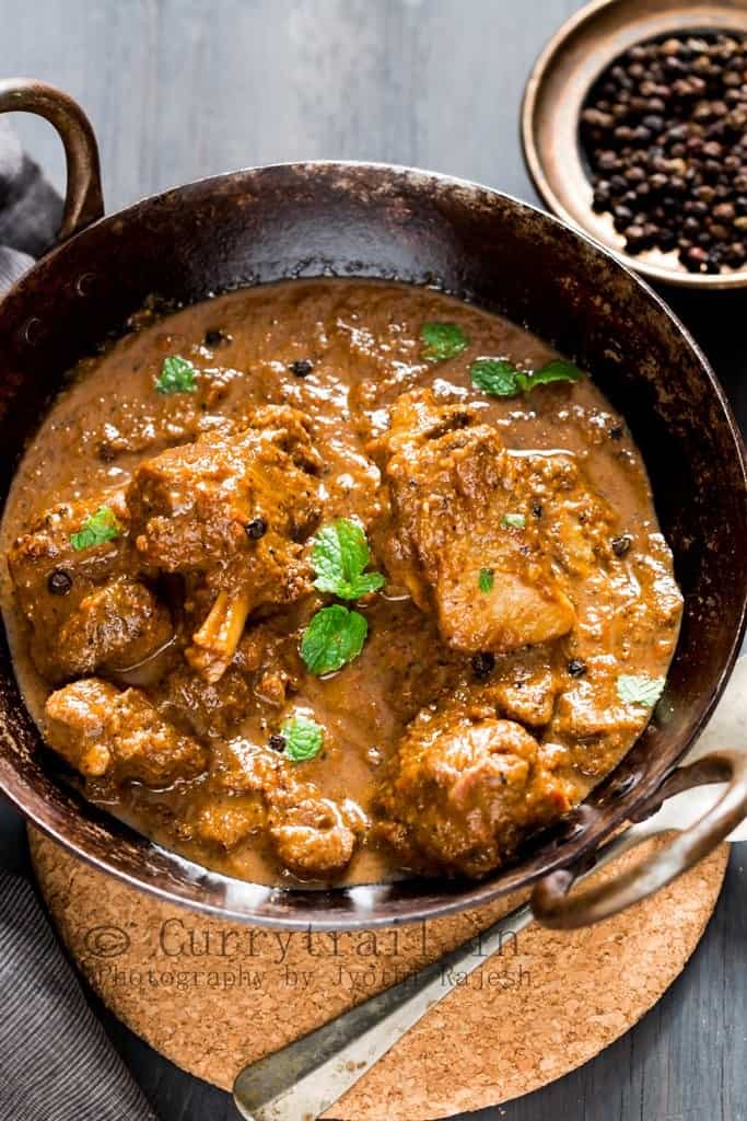 spicy pepper mutton curry served in cast iron pan with spoon on the side