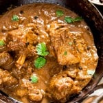 spicy pepper mutton curry served in cast iron pan with spoon on the side