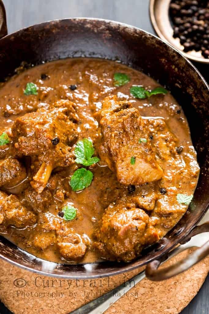 spicy pepper mutton curry served in cast iron pan with spoon on the side