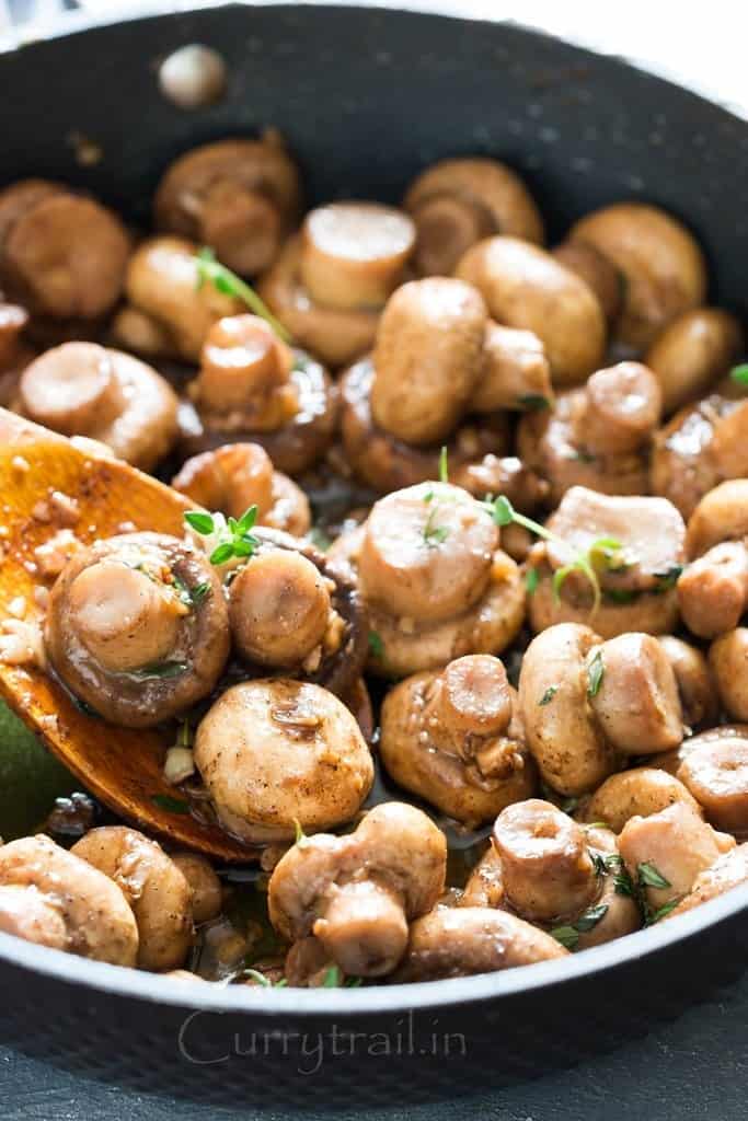 cooking sauteed mushroom recipe with butter garlic and thyme in skillet