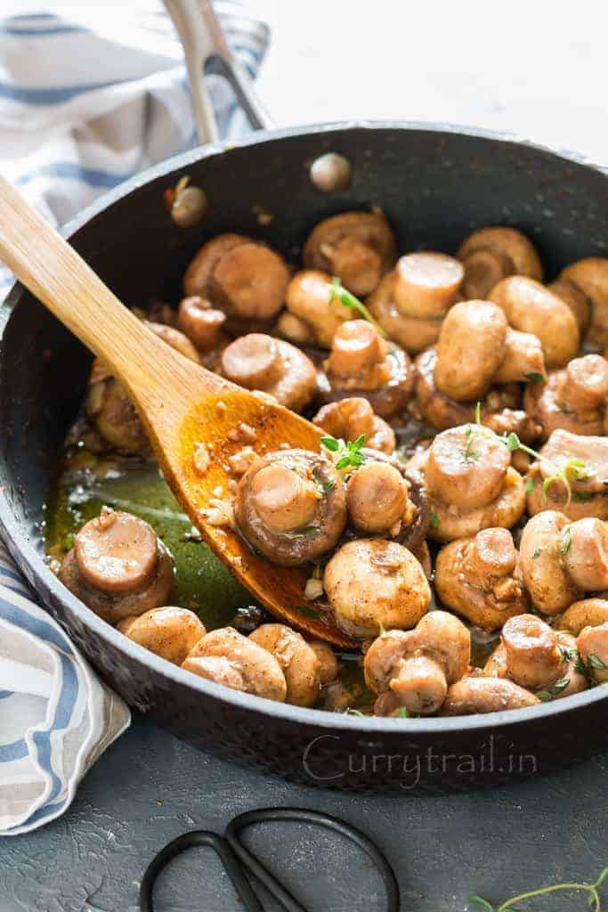 cooking sauteed mushroom recipe with butter garlic and thyme in skillet