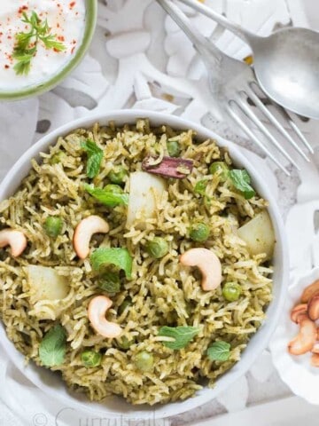 Homemade Mint Pulao in white bowl with raita on the side