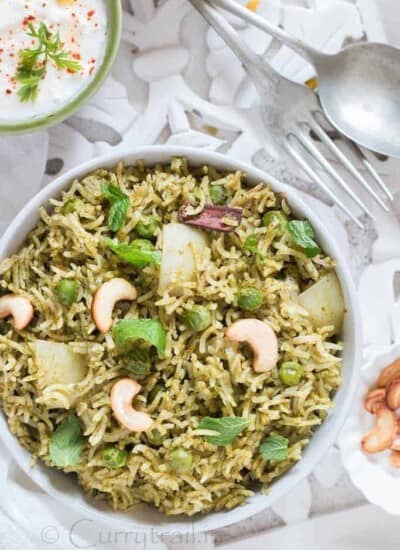 Homemade Mint Pulao in white bowl with raita on the side