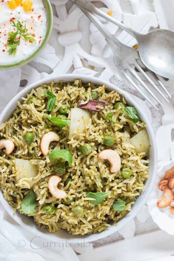 Homemade Mint Pulao in white bowl with raita on the side