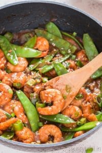 shrimp stir fry in a skillet with snow peas