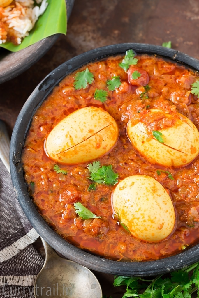 Close up of a black bowl with South Indian spicy egg curry with coriander leaf garnish