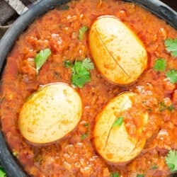 3 eggs in a black bowl with South Indian Spicy Egg Curry