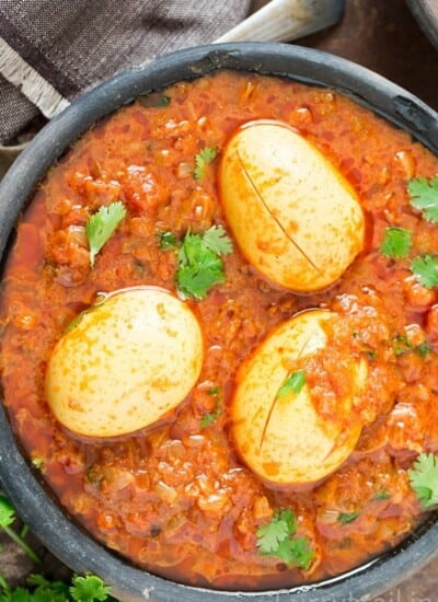 3 eggs in a black bowl with South Indian Spicy Egg Curry