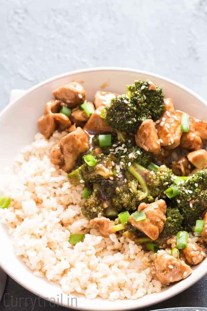 chicken rice and broccoli stir fry in a white bowl with brown rice