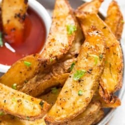 A plate with Crispy Garlic Parmesan Baked Potato Wedges and a small bowl of ketchup on side