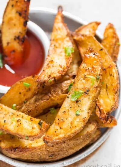 A plate with Crispy Garlic Parmesan Baked Potato Wedges and a small bowl of ketchup on side