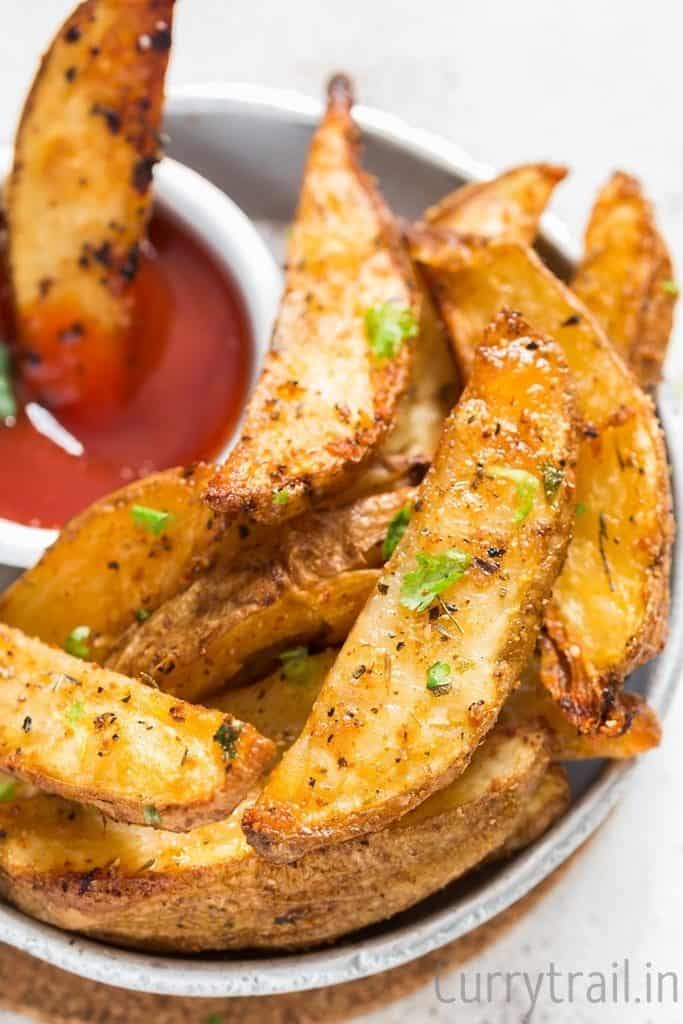 A plate with Crispy Garlic Parmesan Baked Potato Wedges and a small bowl of ketchup on side