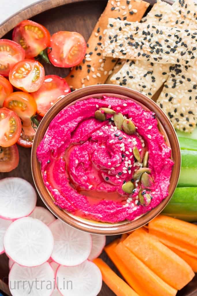 snack platter with raw veggie stick and roasted beet hummus in the center