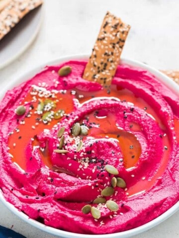 roasted beet hummus in a white bowl with cracker